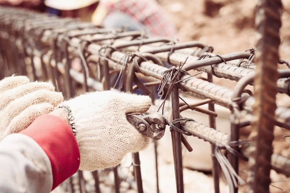 Construction workers are installing steel rods in reinforced concrete beam